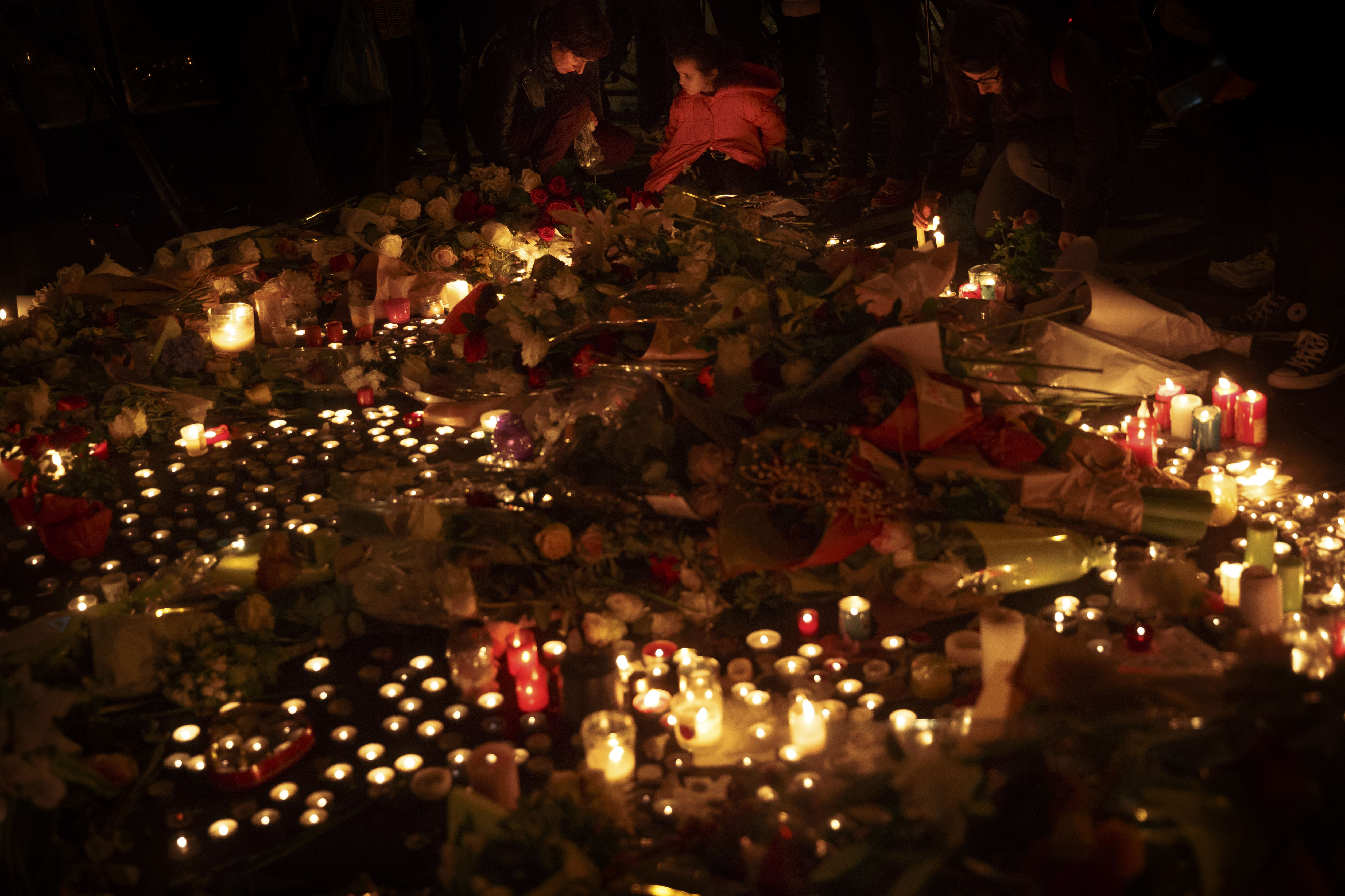 People light candles while outside The Belle Equipe restaurant in Paris, Saturday, Nov. 14, 2015, a day after the attacks on Paris. French President Francois Hollande vowed to attack Islamic State without mercy as the jihadist group admitted responsibility Saturday for orchestrating the deadliest attacks inflicted on France since World War II. (AP Photo/Daniel Ochoa de Olza)